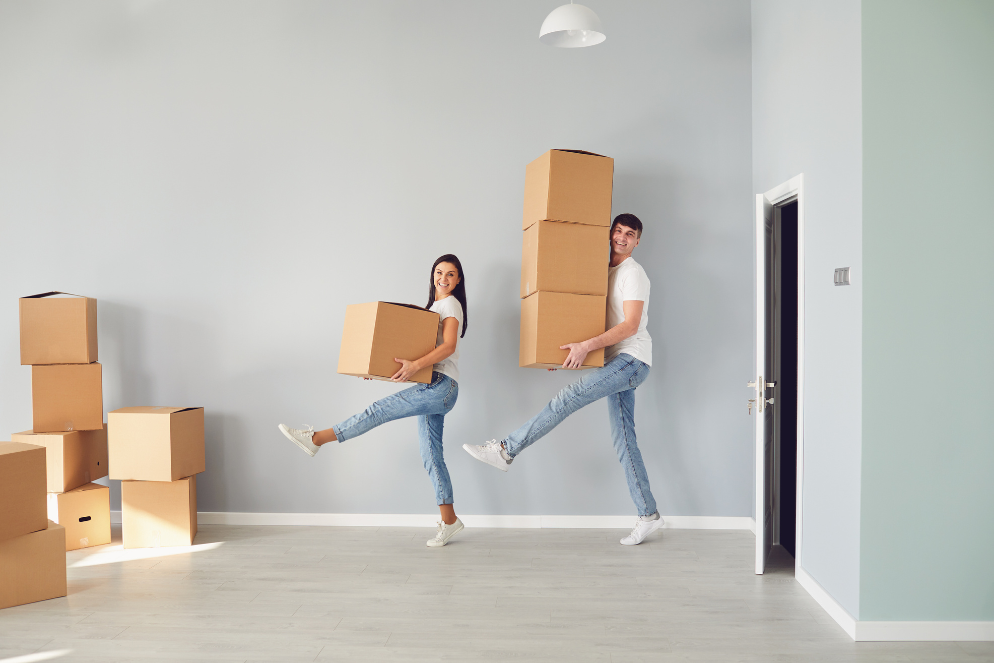 Funny Middle-Aged Couple with Cardboard Boxes Smiling in a New Apartment.